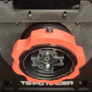 May include: Close-up of a red 3D printed knob with a black centre and the word "PROS" printed on the side. The knob is attached to a black device with the text "TS-PC RACER" visible.