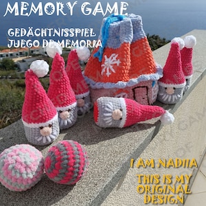 May include: A memory game featuring a crocheted house and gnomes. The game includes two pink and gray balls and a bag for storing the pieces. The text "MEMORY GAME", "GEDÄCHTNISSPIEL", and "JUEGO DE MEMORIA" is visible on the image. The text "I AM NADIA THIS IS MY ORIGINAL DESIGN" is also visible on the image.