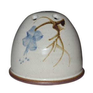 May include: A ceramic salt shaker with a rounded, bell-like shape. The off-white surface is decorated with a blue floral design and brown branch-like accents. The base and rim are a dark brown color.