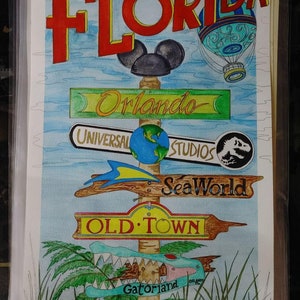 Puede incluir: Una pintura de acuarela de un poste indicador con la palabra "Florida" en letras rojas en la parte superior. El poste indicador tiene varias señales direccionales que apuntan a diferentes atracciones en Florida, incluyendo "Orlando", "Universal Studios", "Sea World", "Old Town" y "Gatorland".