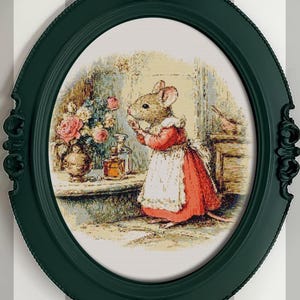 Pu&ograve; includere: Stampa incorniciata in una cornice ovale verde scuro. L'immagine raffigura un topo con un vestito rosso e un grembiule bianco, in piedi vicino a un tavolo con fiori e bottiglie. La cornice ha dettagli decorativi.