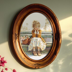 May include: An oval, wooden framed print of a young girl sitting on a bench, with a basket of flowers. The girl is wearing a yellow coat and floral dress. The frame has a distressed, antique finish.