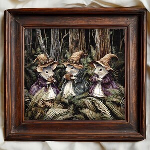 Può includere: Opera d'arte incorniciata con tre topi vestiti con costumi da strega, ognuno con un cappello a punta e abiti viola. Sono circondati da felci in un ambiente forestale, con una cornice in legno marrone scuro.