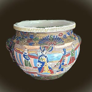 May include: A decorative ceramic bowl with a wide rim and two handles. The bowl features a colorful, detailed scene of figures in traditional clothing, with blue, red, and gold accents. The rim has a detailed pattern.