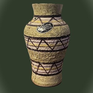 May include: A textured, olive-green vase with a geometric pattern of black and white triangles and horizontal stripes. The vase has a label that reads "Rossini Originals Hand Decorated Italy."