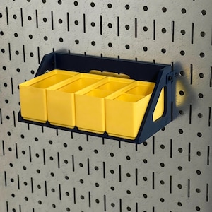 May include: A wall-mounted storage unit with four yellow bins. The unit is supported by a dark blue frame and is designed to attach to a pegboard. The pegboard has a pattern of evenly spaced holes and slots.