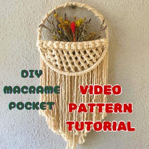 May include: DIY macrame pocket video pattern tutorial. A macrame wall hanging with a pocket and a fringe. The pocket is filled with dried flowers.
