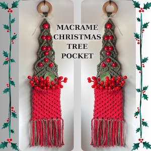 以下が含まれることがあります： 赤とグレーのマクラメクリスマスツリーポケット。赤いベリーと緑の葉で飾られています。ツリー型のデザインは、吊り下げ用の木製リングと「MACRAME CHRISTMAS TREE POCKET」のテキストが特徴です。