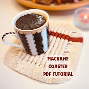 May include: A white macrame coaster with red accents and fringe. A cup of coffee sits on top of the coaster. The text "MACRAME COASTER PDF TUTORIAL" is printed on the coaster.