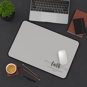 May include: A gray desk mat with a black border and the text "faith" in a cursive font. The text is accompanied by the quote "For with God all things are possible."  Mark 10:27.