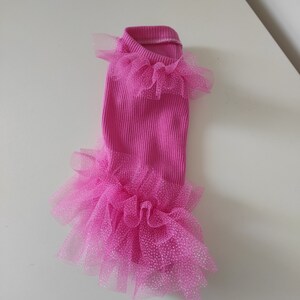 Peut inclure: Une robe rose vif pour animaux de compagnie, avec un corsage c&ocirc;tel&eacute; et des couches de tulle scintillant autour du cou et de l'ourlet. Con&ccedil;ue pour un petit chien ou chat, elle ajoute une touche glamour.