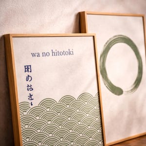 Könnte beinhalten: Zwei gerahmte Kunstdrucke mit Holzrahmen. Ein Druck zeigt einen grünen Kreis, der andere japanischen Text und ein grünes Wellenmuster. Der Text lautet "wa no hitotoki" und andere japanische Schriftzeichen.