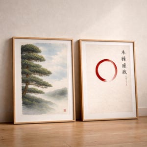 May include: Two framed art prints. One features a detailed painting of a tree on a misty hillside with a blue sky. The other print has a red circle and Japanese text on a cream background. Both are in light wood frames.