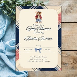 May include: A baby shower invitation with a blue and red tartan pattern. The invitation features a cartoon teddy bear wearing a blue shirt and jeans. The text on the invitation reads "Join us for a Baby Shower celebrating Amelia Jackson. Sunday, March 18th at 6 PM. The Magnolia Manor, 256 Rosewood Avenue, Bellevue Heights, NY 10542."