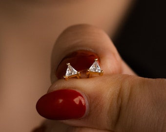 May include: A pair of gold triangle earrings with small clear cubic zirconia stones.