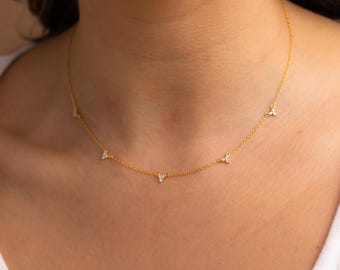 May include: A delicate gold chain necklace with five small triangle-shaped pendants, each set with three tiny clear cubic zirconia stones.