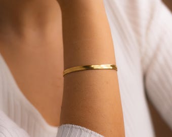 May include: A gold-toned snake chain bracelet.