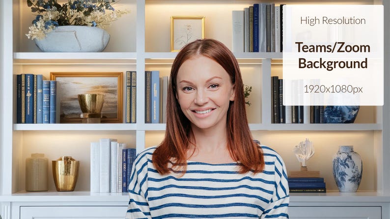 May include: A woman with long red hair smiles at the camera. She is wearing a blue and white striped shirt. The background is a white bookshelf with books and decorative items.