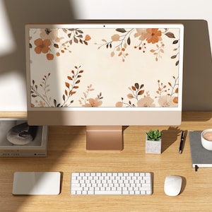 May include: A desktop computer with a floral wallpaper on the screen. The computer is on a wooden desk with a keyboard, mouse, a small potted plant, a notebook, and a cup of coffee.