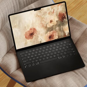 May include: A black laptop computer with a floral wallpaper on the screen. The laptop is sitting on a light brown chair with a blue trim.