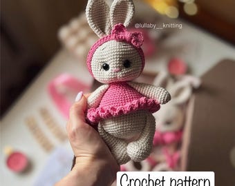 May include: A beige crocheted rabbit doll featuring a pink dress and a matching pink headband with a small bow. The rabbit has dark eyes and embroidered facial features. The text "Crochet pattern" is visible in the lower right corner.