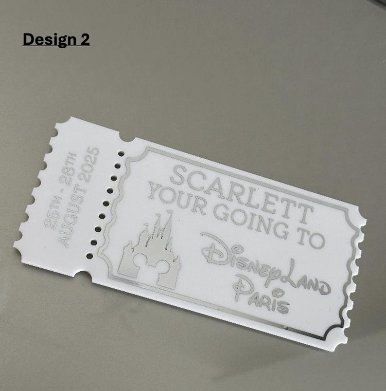May include: A white ticket-shaped keepsake with the text "SCARLETT YOUR GOING TO Disneyland PARIS" and a castle graphic. The ticket also includes the dates "25th - 28th AUGUST 2025" and the words "Design 2".