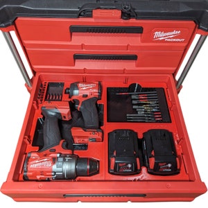 May include: A red Milwaukee Packout tool box containing two Milwaukee Fuel power tools, a drill and a driver, and two batteries. The tools are in a foam insert with a compartment for drill bits.