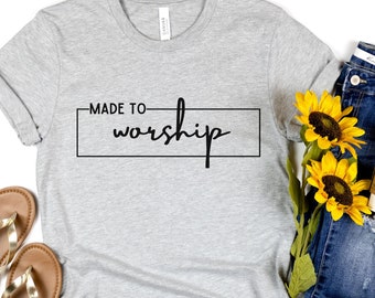 Può includere: Maglietta grigia con il testo "MADE TO worship" in un rettangolo nero.