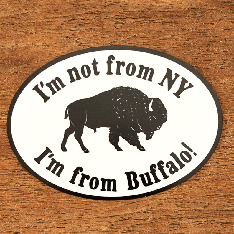May include: White oval sticker with black text and a black silhouette of a buffalo. The text reads "I'm not from NY I'm from Buffalo!"