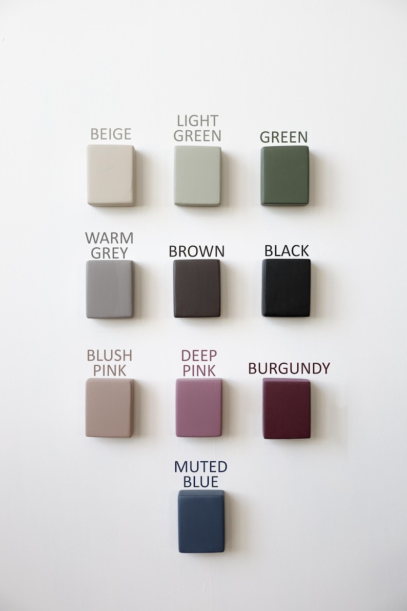 May include: A collection of twelve square-shaped objects in various colors, including beige, light green, green, warm grey, brown, black, blush pink, deep pink, burgundy, and muted blue. Each object has a color name printed above it.