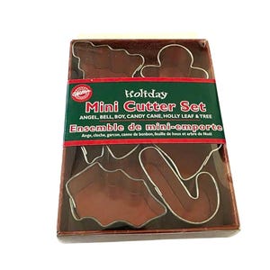 May include: A boxed set of mini cookie cutters in various holiday shapes, including an angel, bell, boy, candy cane, holly leaf, and tree. The packaging features the text "Holiday Mini Cutter Set" in English and French.
