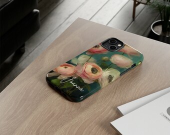 May include: A personalized phone case with a floral design. The case features a teal background with pink and white flowers. The name "Joanna" is written in white script on the case.