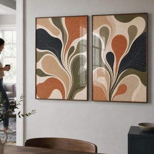 May include: Two rectangular wall art prints featuring abstract, fluid, organic shapes in a palette of burnt orange, sage green, dark charcoal, and cream. Each print displays a symmetrical, flowing pattern with fine, delicate line textures.