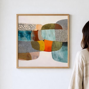 Könnte beinhalten: Abstraktes Kunstwerk in einem Holzrahmen. Das Kunstwerk zeigt eine farbenfrohe Komposition aus Formen in Blau-, Orange-, Grün- und Brauntönen. Verschiedene Texturen und Muster sind in das Design integriert. Das Gemälde hängt an einer weißen Wand.