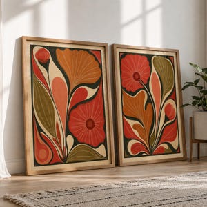 May include: Two rectangular framed wall art prints featuring abstract floral designs in a palette of burnt orange, deep red, olive green, and cream. The illustrations display stylized flowers and large, flowing leaves with bold, dark outlines.
