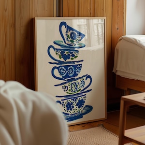 May include: A framed art print featuring a stack of five blue and white teacups with floral designs. The artwork is displayed in a light-colored wooden frame, adding a touch of elegance to the room's decor.