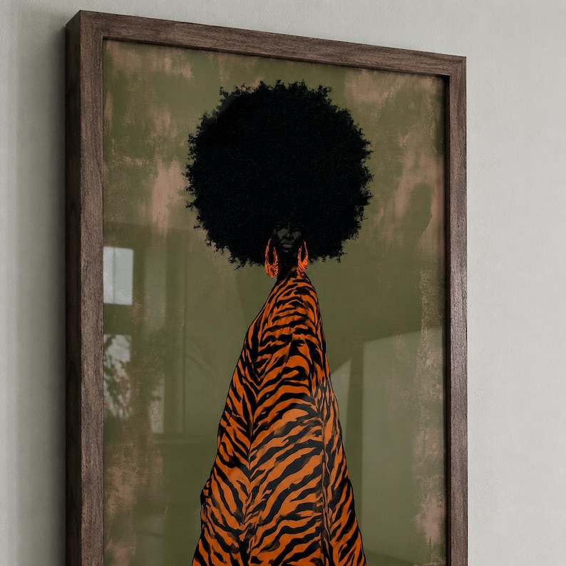 May include: A framed wall art print featuring a figure with a large black afro hairstyle and bright orange hoop earrings. The figure is wearing a garment with a bold black and orange tiger stripe pattern against a muted olive green background.