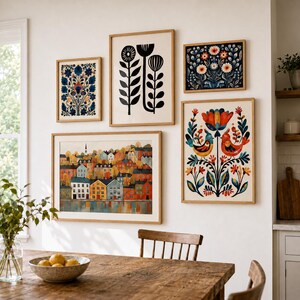 Puede incluir: Una pared de galer&iacute;a con cinco l&aacute;minas de arte enmarcadas. La colecci&oacute;n incluye un paisaje de casas coloridas, una ilustraci&oacute;n floral en blanco y negro, y tres l&aacute;minas de tem&aacute;tica bot&aacute;nica o de aves con tonos azules, naranjas y rojos.