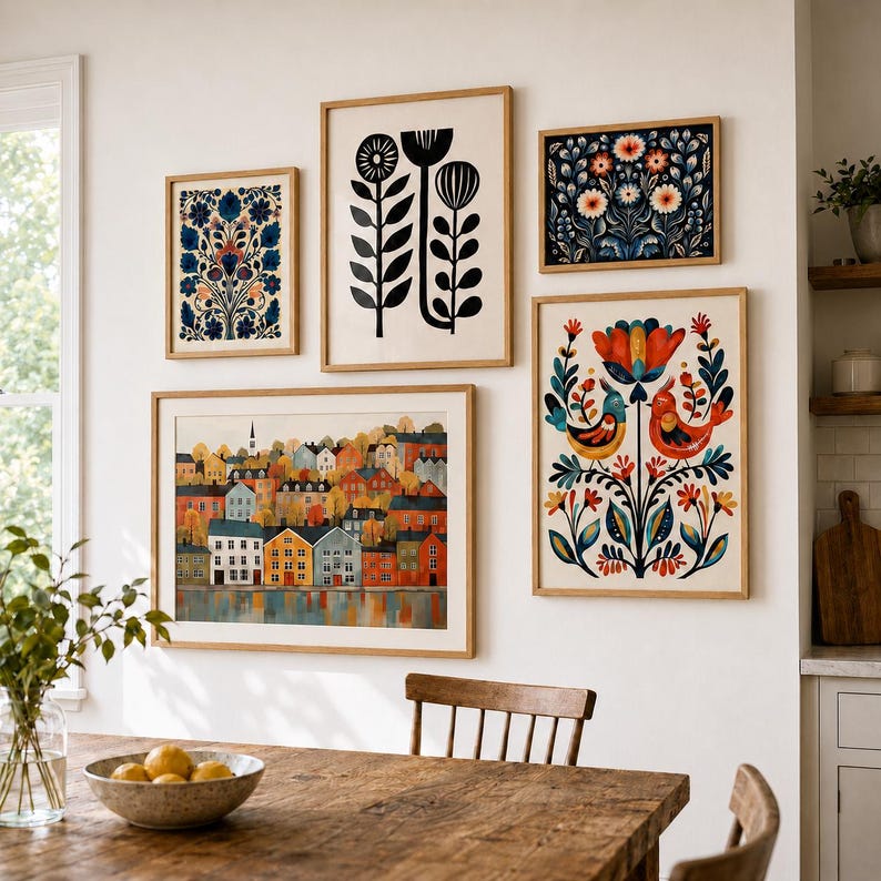 Puede incluir: Una pared de galer&iacute;a con cinco l&aacute;minas de arte enmarcadas. La colecci&oacute;n incluye un paisaje de casas coloridas, una ilustraci&oacute;n floral en blanco y negro, y tres l&aacute;minas de tem&aacute;tica bot&aacute;nica o de aves con tonos azules, naranjas y rojos.