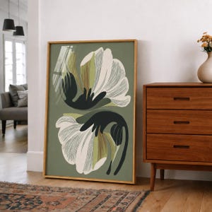Puede incluir: Una impresi&oacute;n art&iacute;stica enmarcada con un dise&ntilde;o floral estilizado. La obra de arte muestra dos grandes flores abstractas en blanco y verde oliva sobre un fondo verde apagado. El marco es de color madera natural, complementando los tonos terrosos de la obra.
