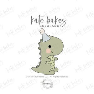 May include: A light olive green dinosaur illustration wearing a light blue party hat with a white pom-pom. The dinosaur has a cream-colored belly, pink cheeks, and a black eye. The text "kate bakes COLORADO" appears above the dinosaur.