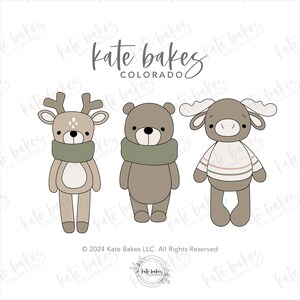 May include: Three cartoon animal cookie cutters: a deer, a bear, and a moose. The deer and bear wear green scarves, while the moose sports a striped sweater. The text "kate bakes COLORADO" is at the top.