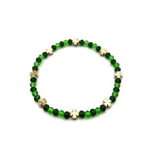 May include: A green crystal bracelet with gold four-leaf clover charms.