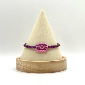 May include: A purple and pink beaded bracelet with a pink flower-shaped charm.