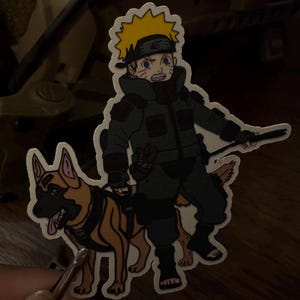 May include: A sticker featuring an anime-style character with spiky yellow hair, wearing a green tactical outfit, and a black headband. The character is accompanied by a brown and black dog with a harness. The sticker has a white border.