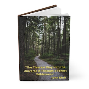 May include: A brown leather-bound journal with a quote by John Muir on the cover. The quote reads "The Clearest Way into the Universe is Through a Forest Wilderness". The background image is a path winding through a lush green forest.