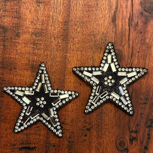 May include: Two black fabric star-shaped patches with silver and clear rhinestones.
