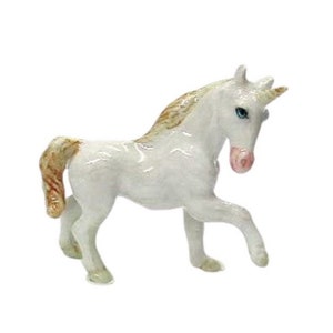 May include: A white porcelain unicorn figurine with a gold mane and tail. The unicorn has blue eyes and a pink nose.