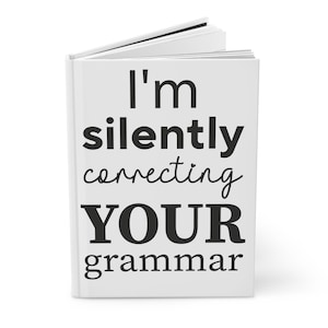 May include: White book with black text that reads "I'm silently correcting YOUR grammar".