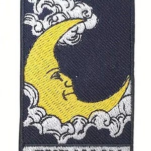 May include: A black and white embroidered patch with a yellow crescent moon and white clouds. The text "THE MOON" is printed in white at the bottom of the patch.
